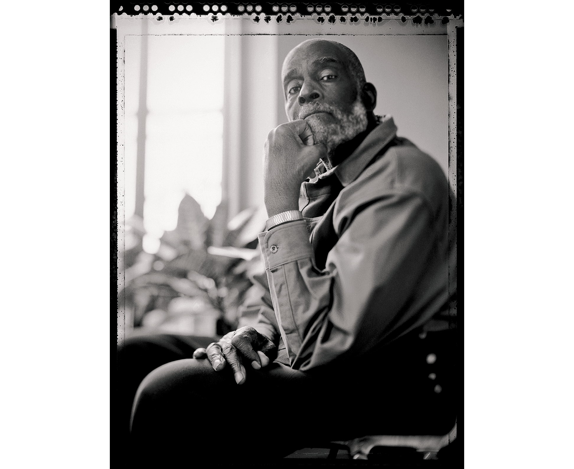 Mel King poses for the camera, his hand raised to his chin, in a black and white photograph.